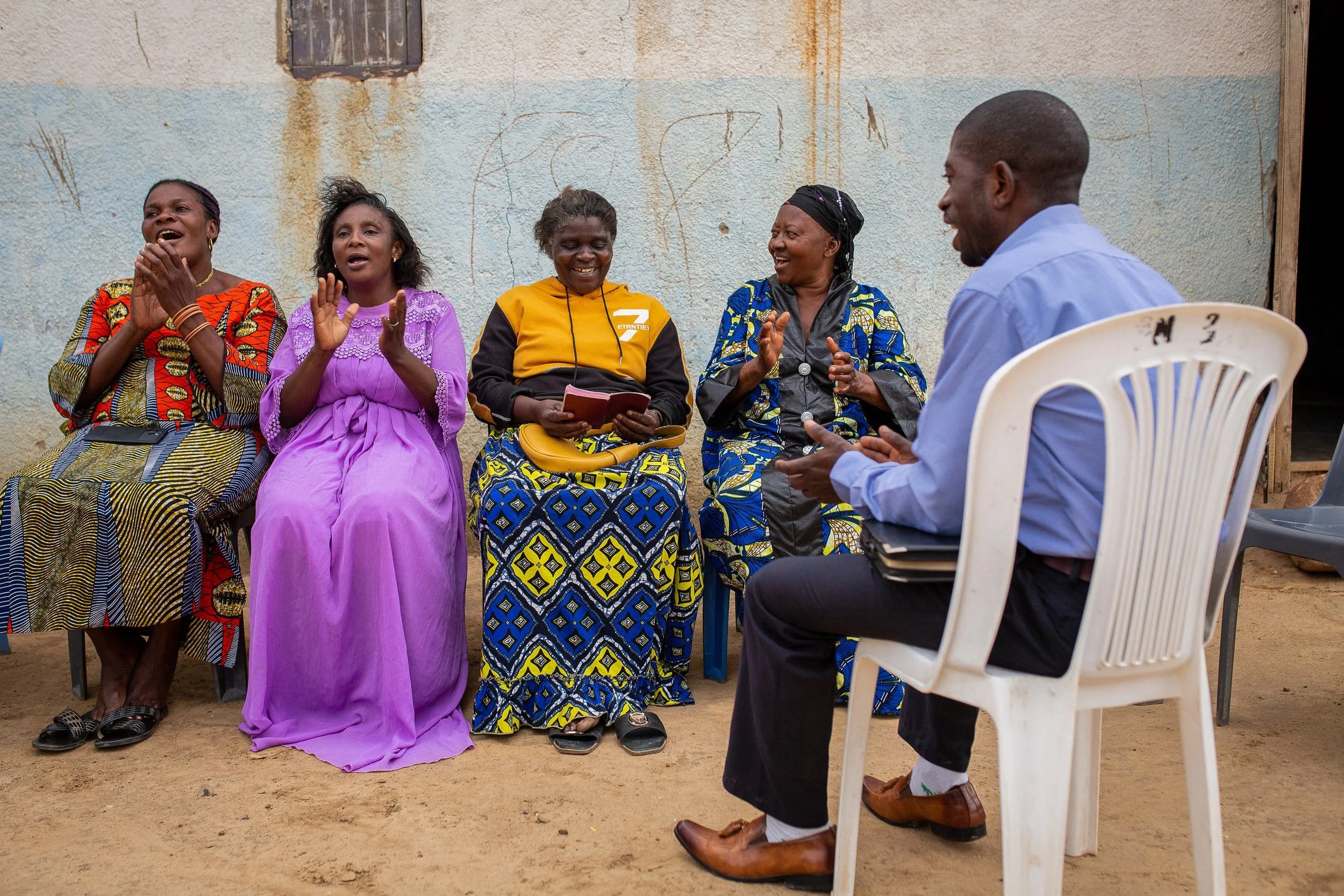 Joshua sits and sings with some of his church members during an evening gathering. 