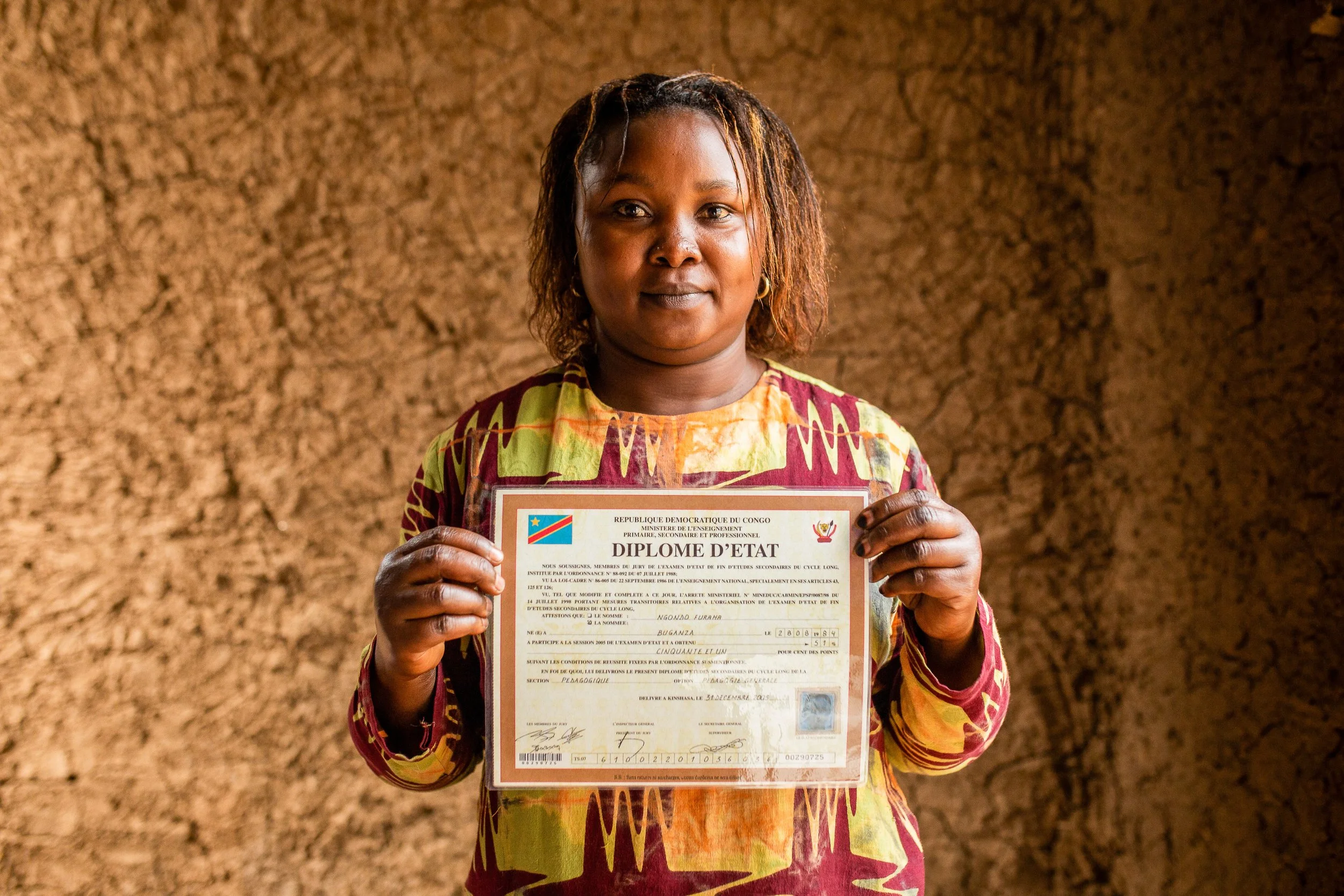 Furaha holds out her diploma which she carried with her from the DRC