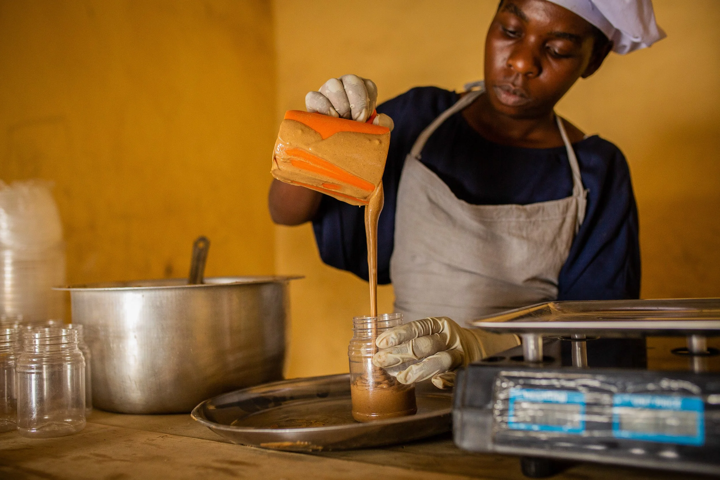 A NutriShield employee pours peanut butter into a jar 