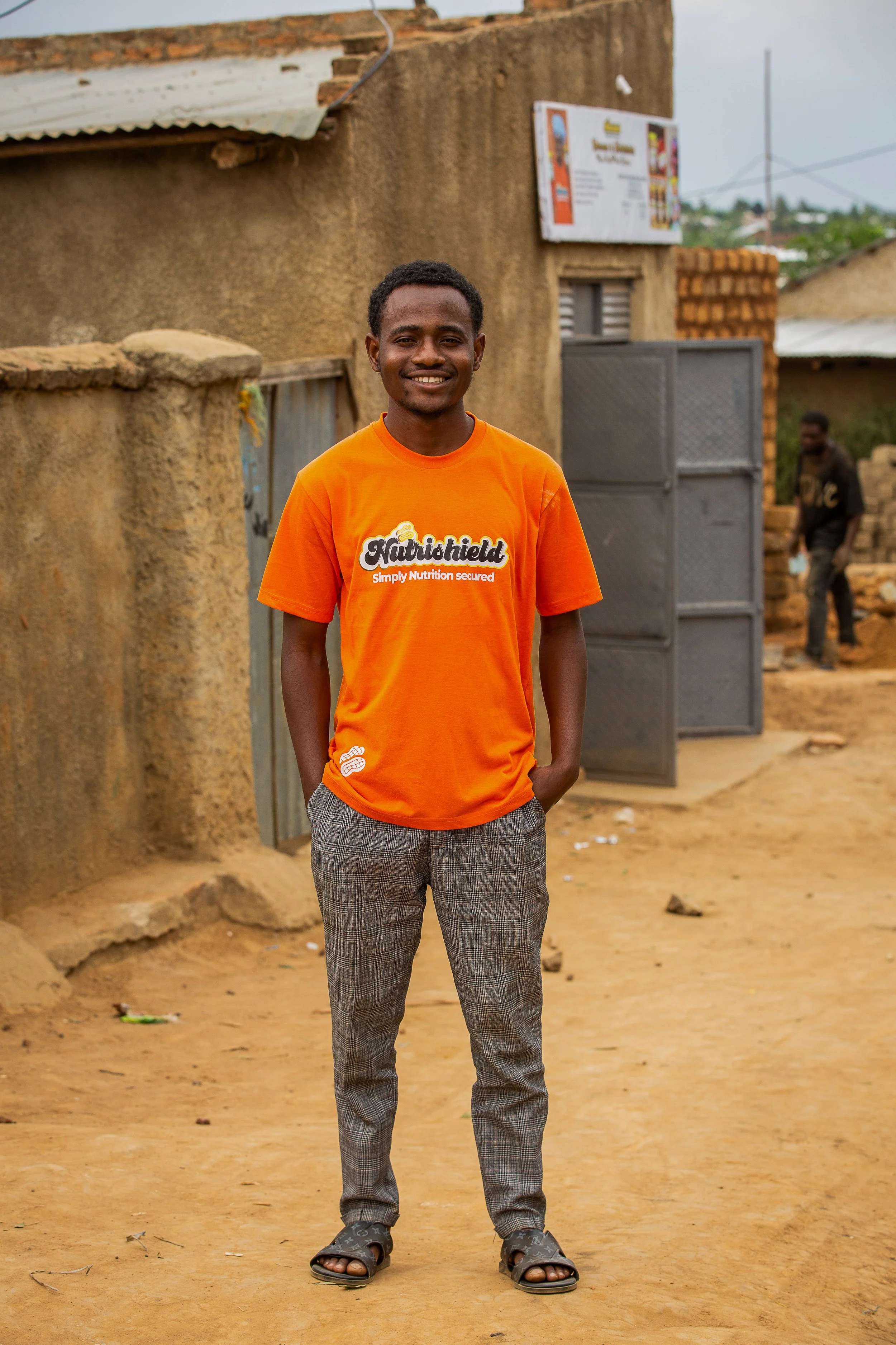 Savino stands in the street outside his business and wears a bright orange t shirt. 