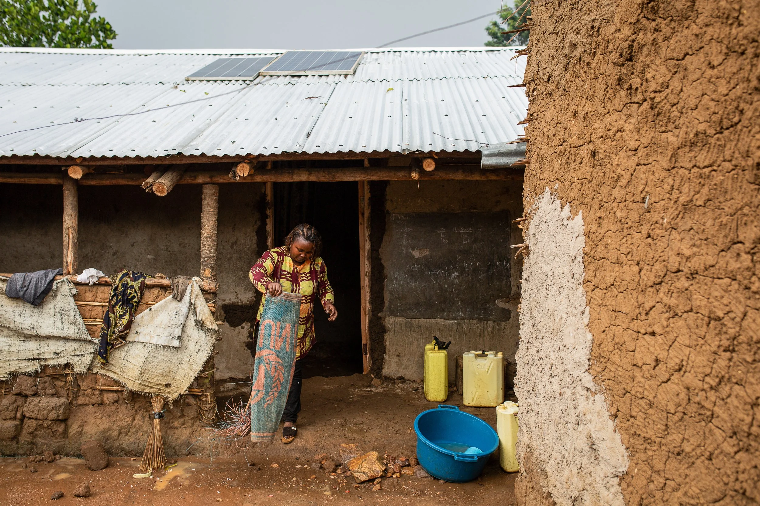 Furaha cleans a carpet outside her home in Rwamwanja. 