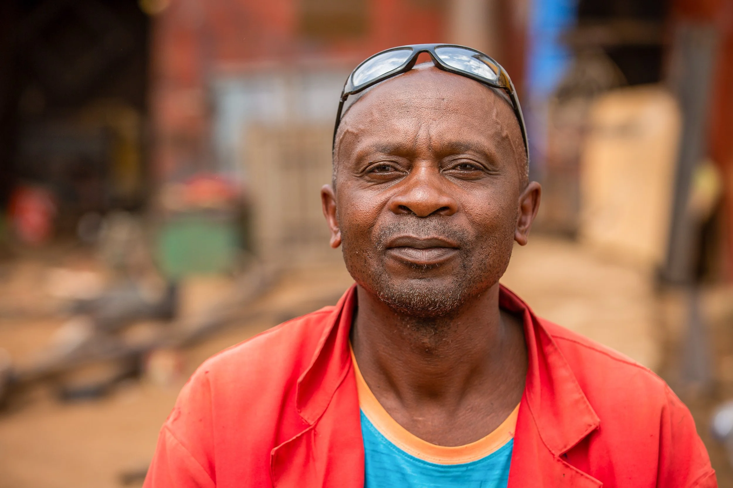 Luhavu looks to the camera wearing a bright red coat and protective glasses on his head.