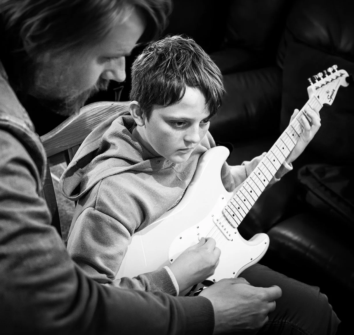 A young boy learning to play an electric guitar with Jonny Dosé.