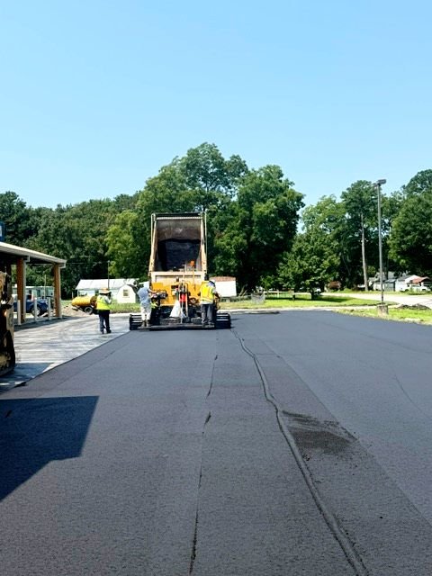 yellow truck pouring asphalt onto road