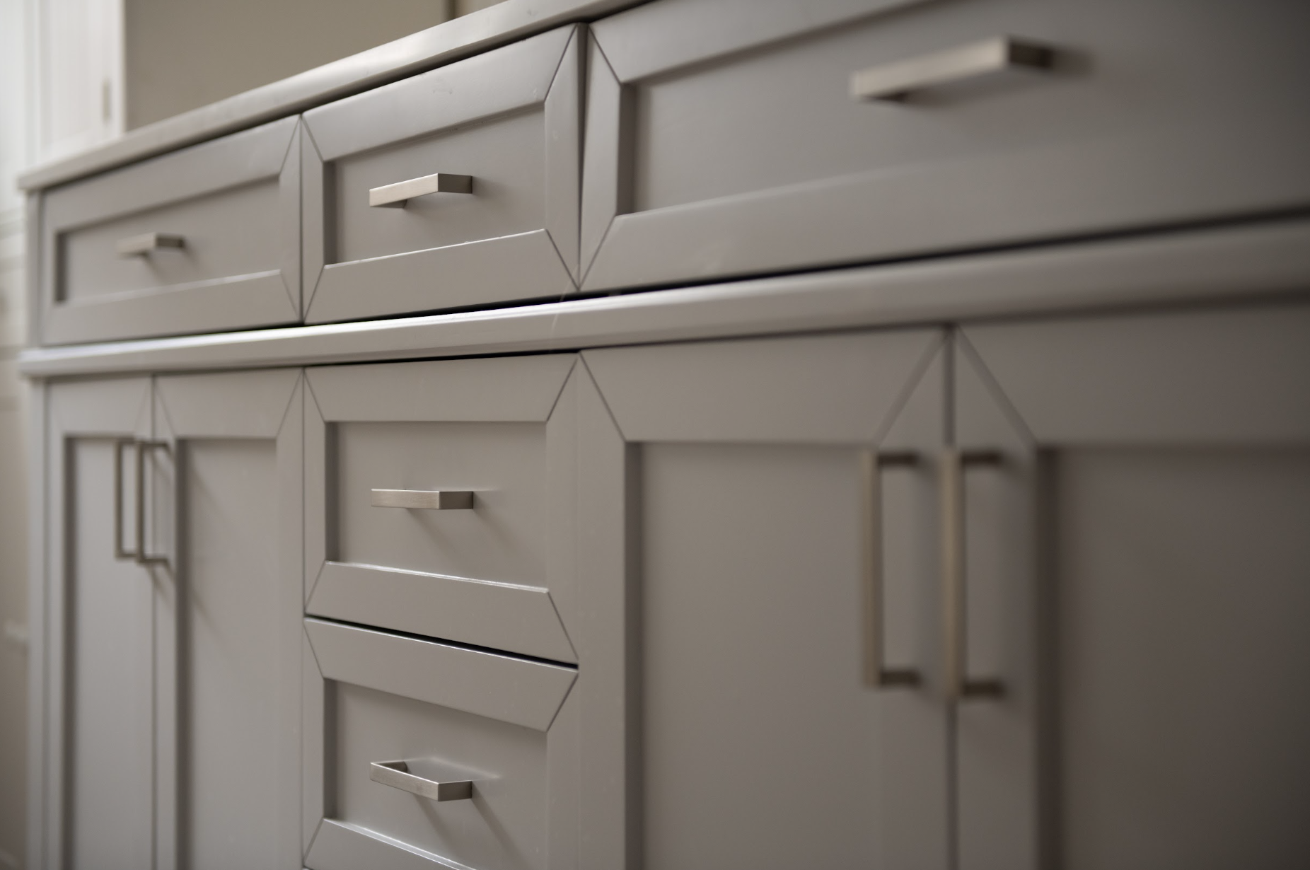 Close-up of a modern, gray cabinet with multiple drawers and doors, featuring sleek silver handles.