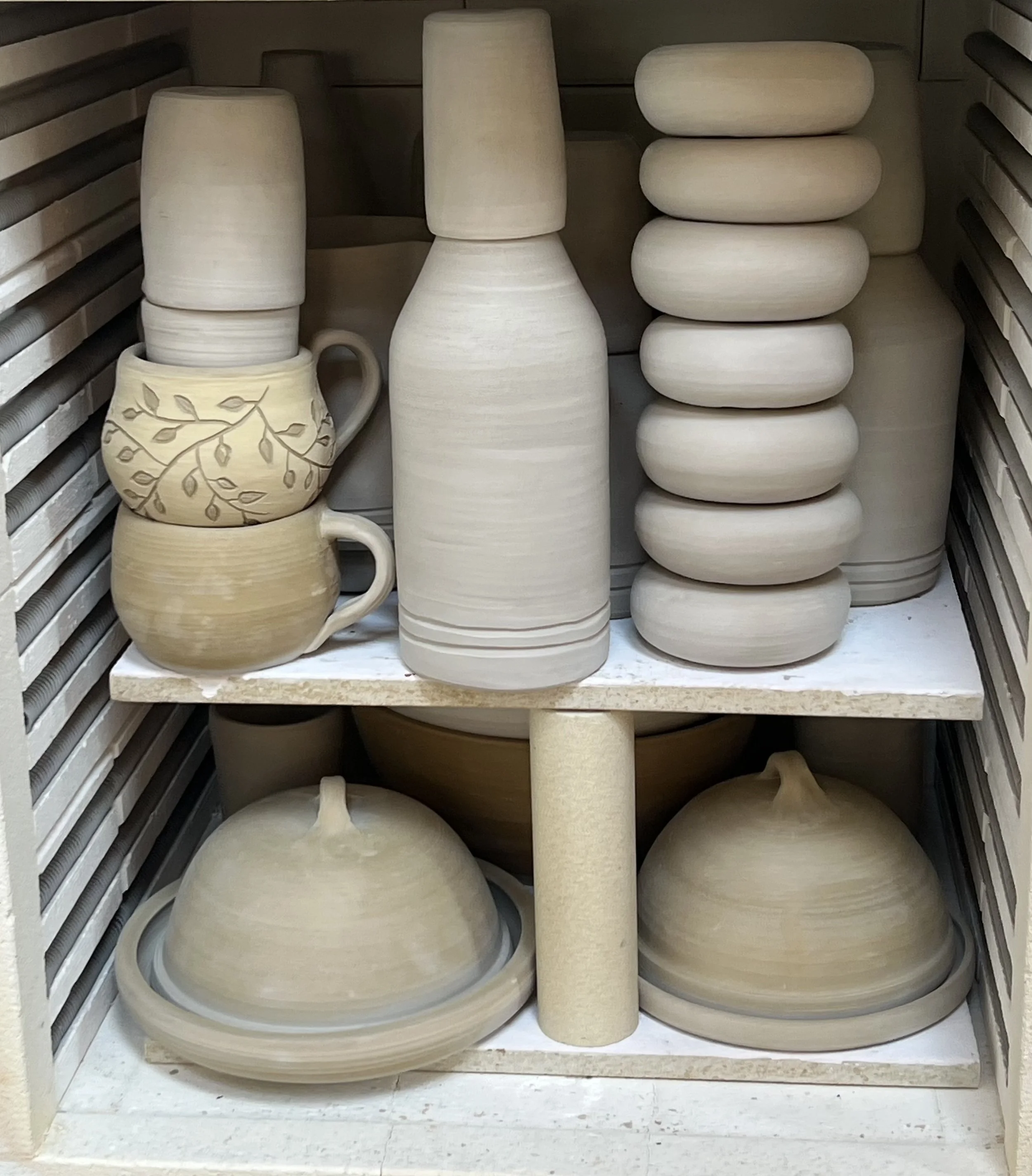 Collection of ceramic pottery including vases, cups, and bowls in a pottery studio.