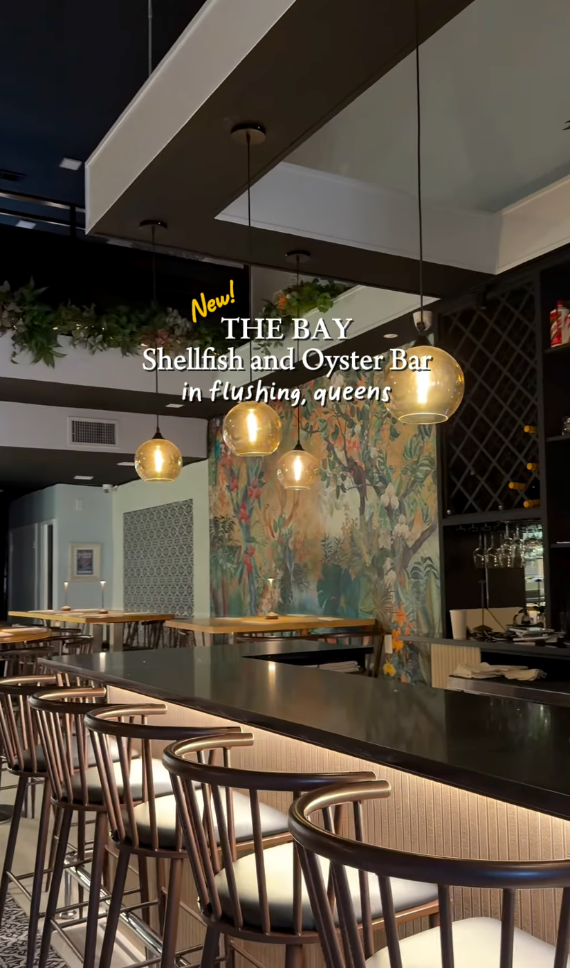 Interior view of The Bay Shellfish and Oyster Bar with pendant lights, bar seating, and a decorative wall mural.