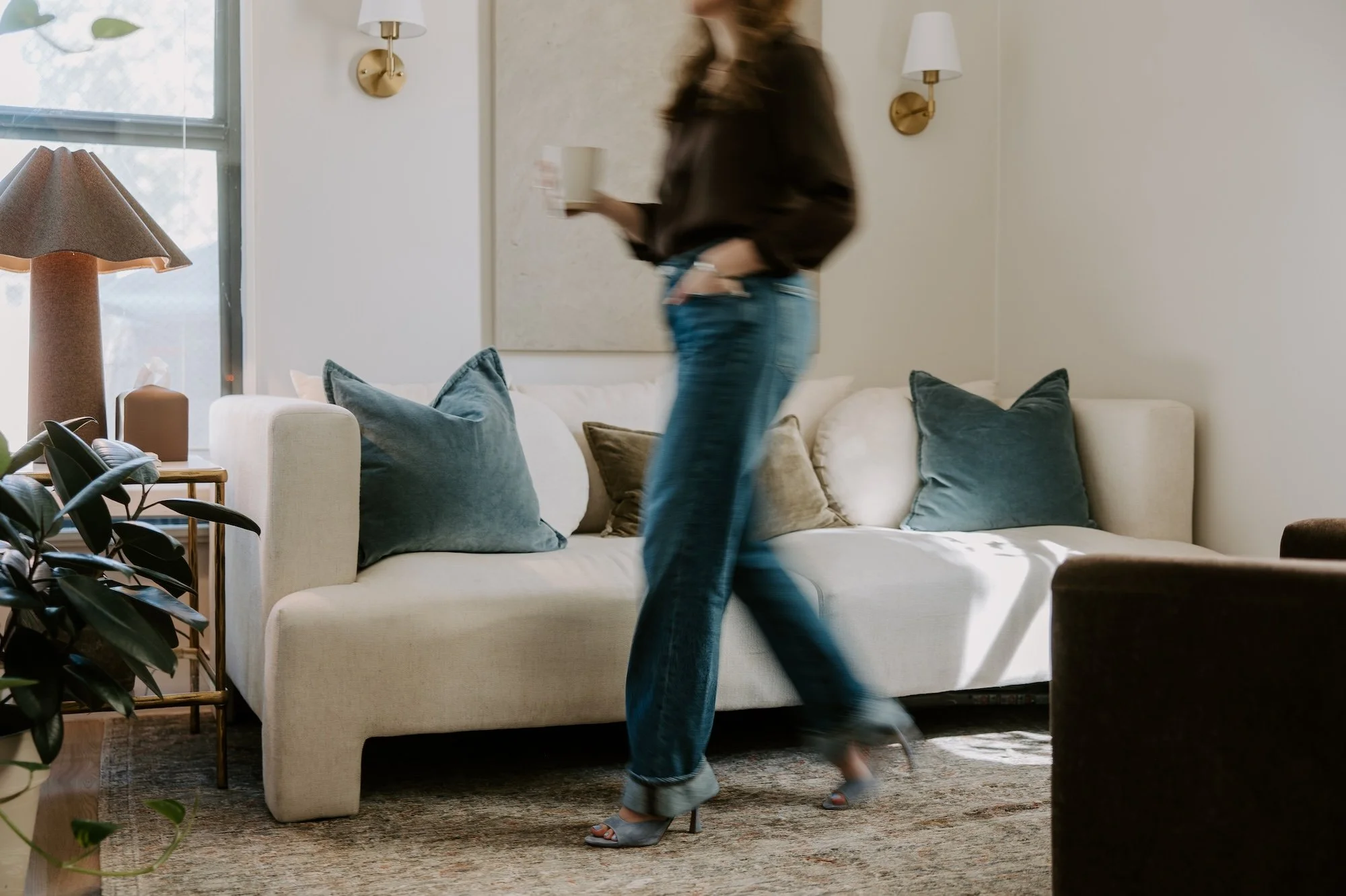 Therapist in jeans and a brown top walking through her Denver therapy office