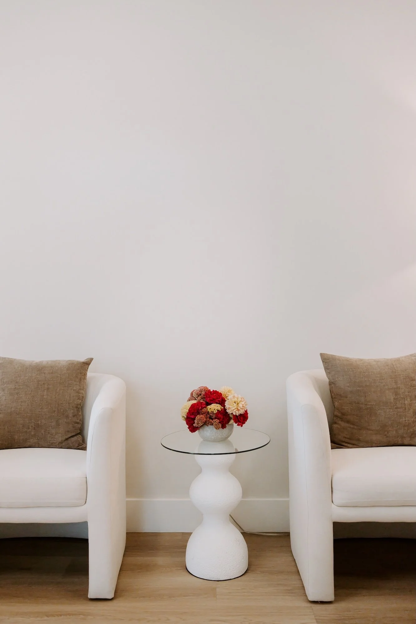 Cream chairs with decorative table and bright flower bouquet in therapy office.