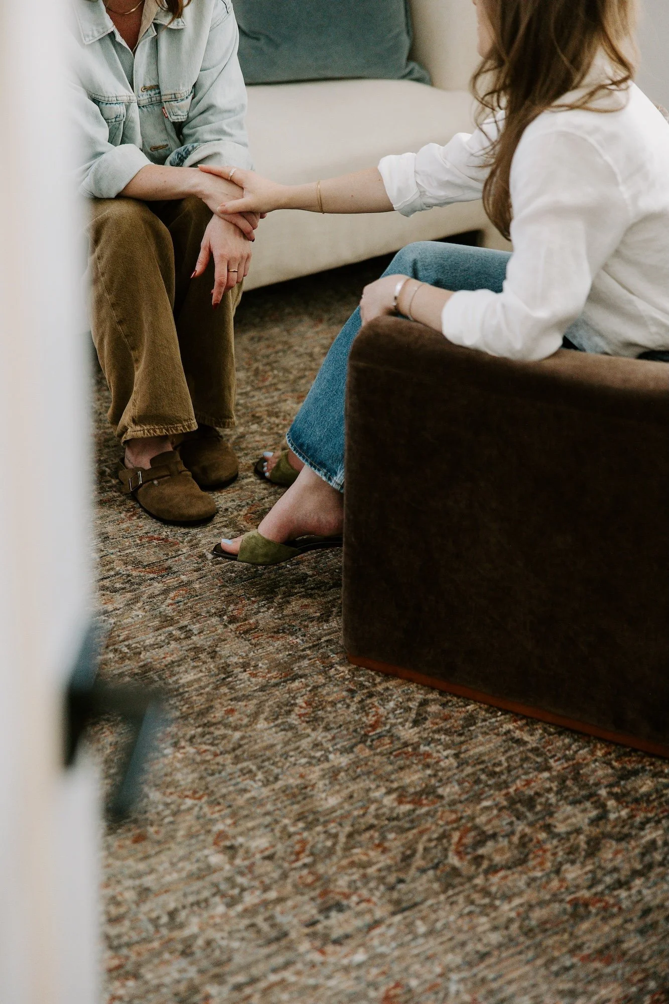 Two people connecting during a therapy session, with the therapist reaching over in support