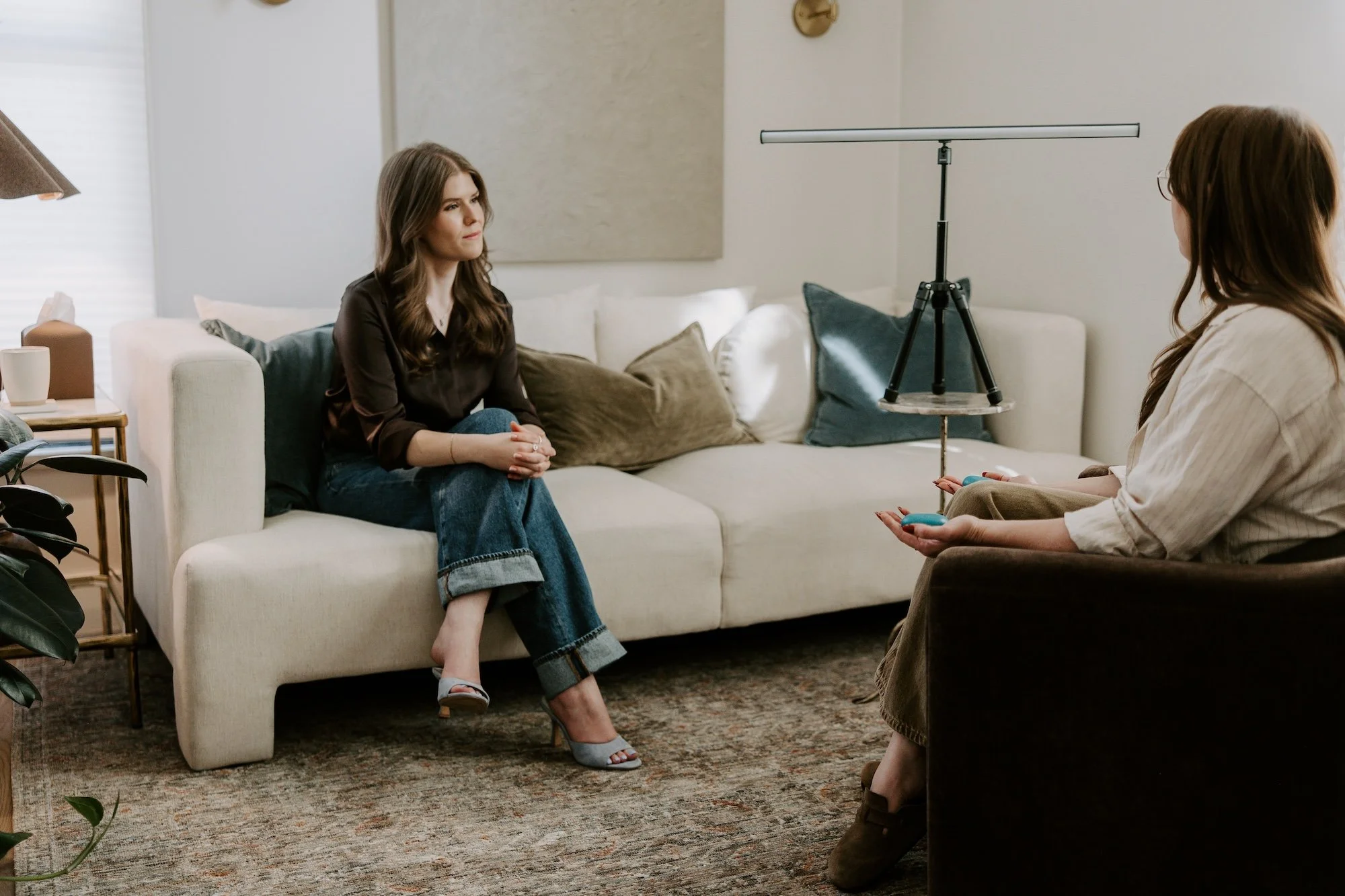 Chadley Zobolas facilitating an EMDR therapy session using a light bar and tactile buzzers with a client in a warm Denver therapy office.