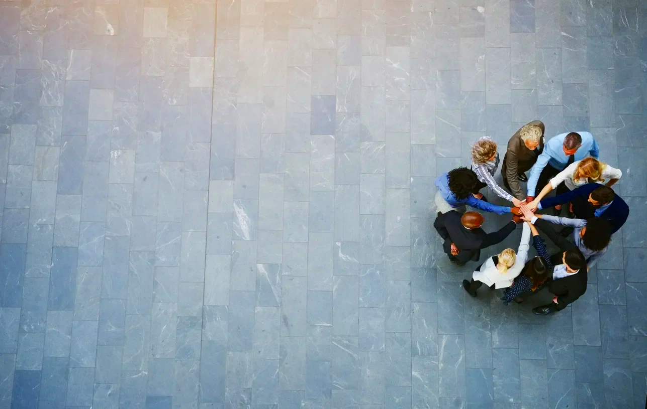 Business team in formal attire putting hands together in a circle during collaboration