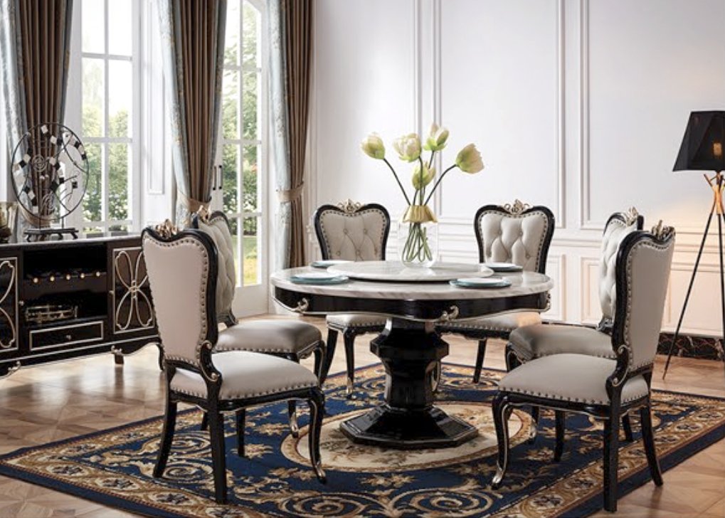 Elegant dining room with a round black and white marble table, six upholstered chairs, floral centerpiece, large windows with brown curtains, and a decorative rug.