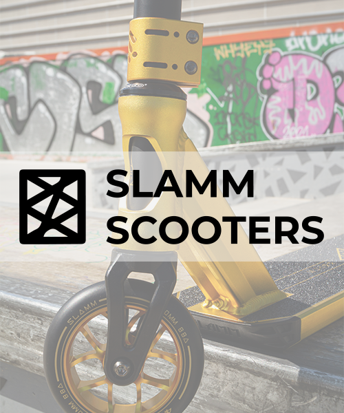 Close-up of a yellow SLAMM scooter parked at an urban skatepark with graffiti on the walls in the background.