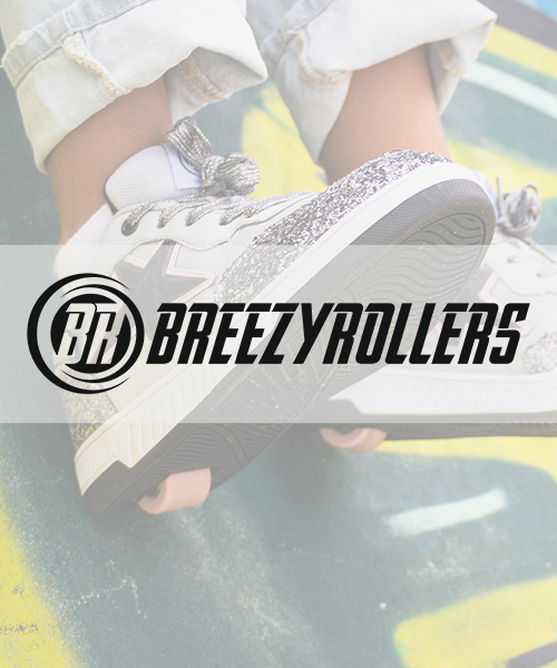 Child wearing Breezy Rollers white sneakers with silver glitter soles, sitting on a colorful striped surface.