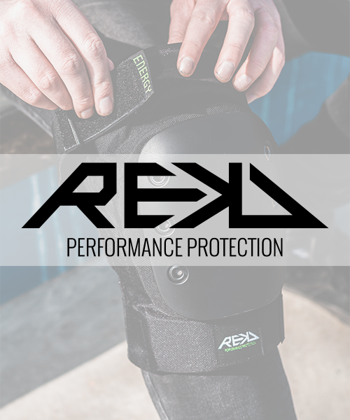 A person adjusting a REKD knee brace with the brand name 'REAL' and the word 'ENERGY' on the strap, promoting performance protection.