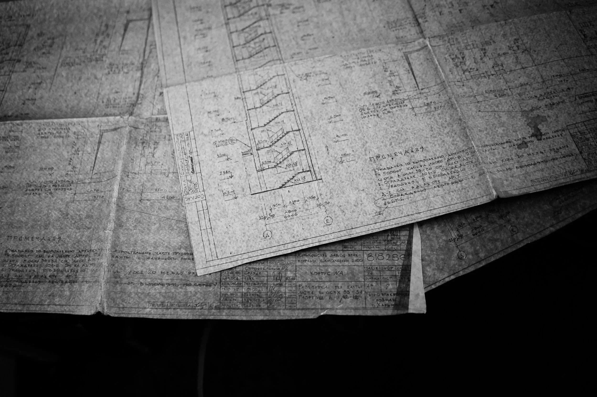 Black and white photograph of a set of detailed architectural blueprints or engineering drawings spread out on a surface.
