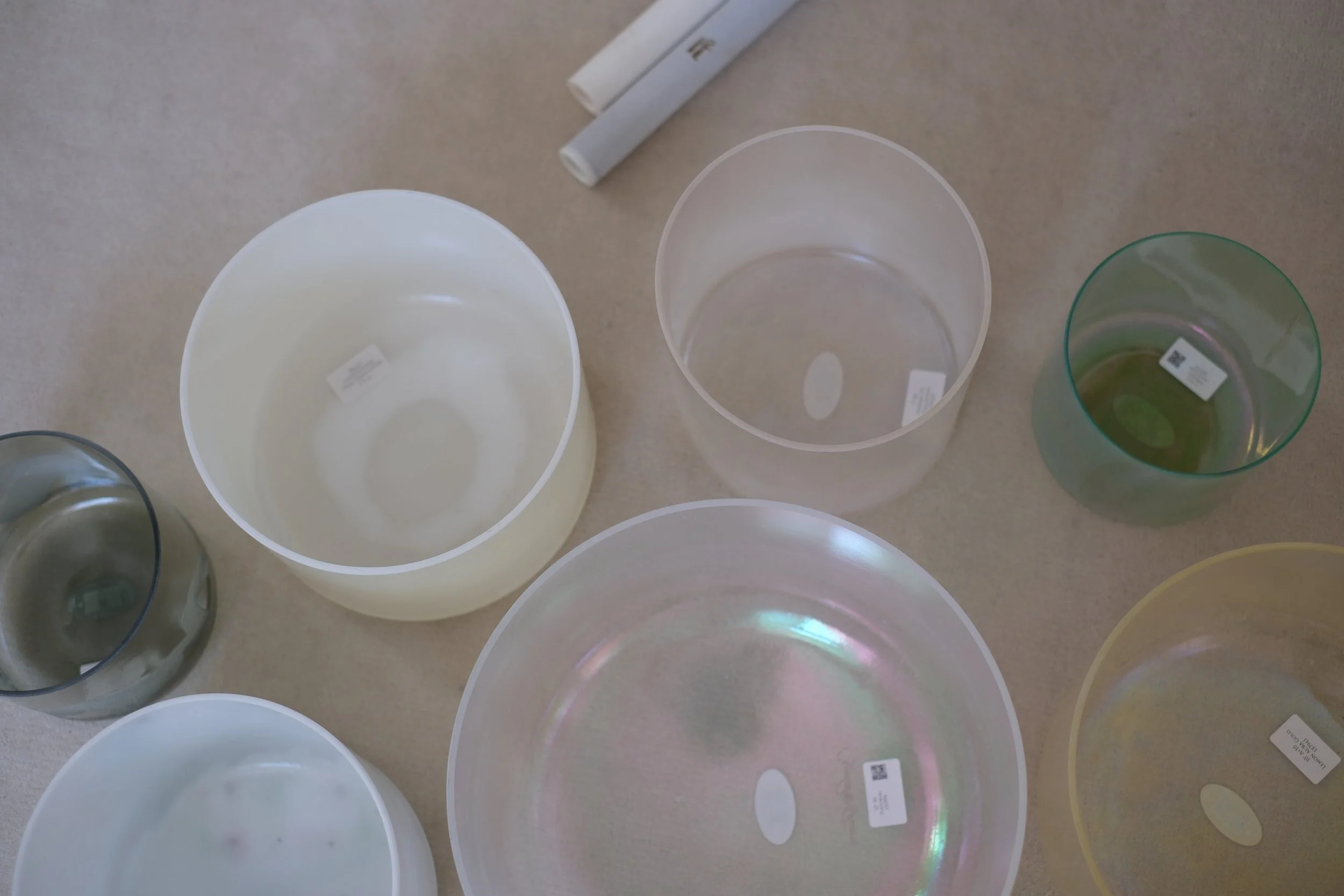Several empty and partially filled colorful plastic vases or containers on a beige surface, with some price tags attached.