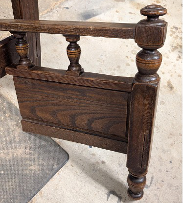 One half of the antique footboard forming a carved side and front leg of the bench.