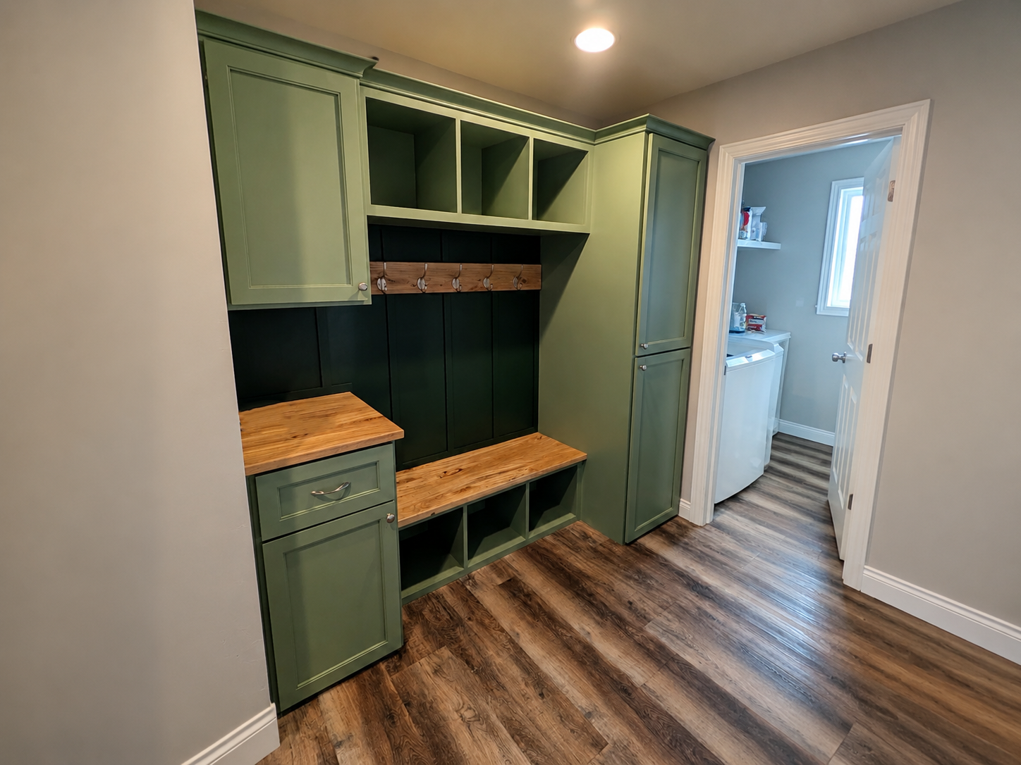 Completed green mudroom built-in with bench and storage cubbies