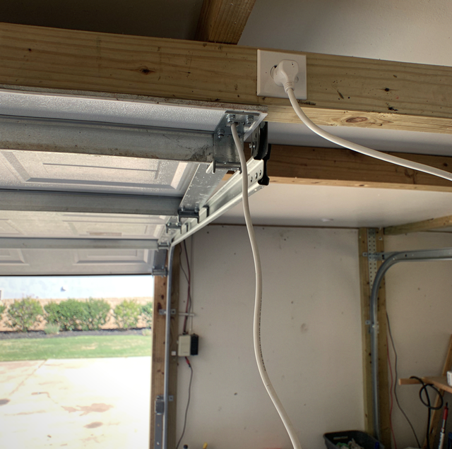 garage door opener motor unit with exposed pairing button on ceiling