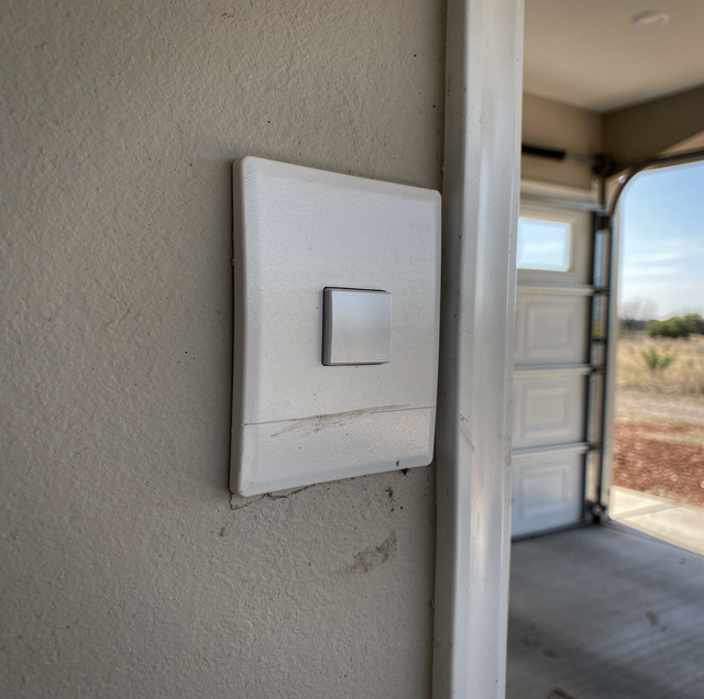 holding garage wall button closing garage door safely