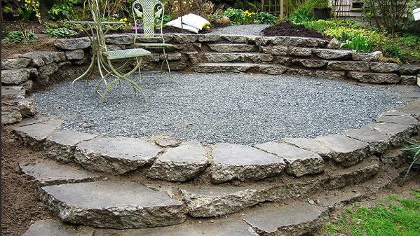 A backyard garden features a small area filled with recycled concrete stone.
