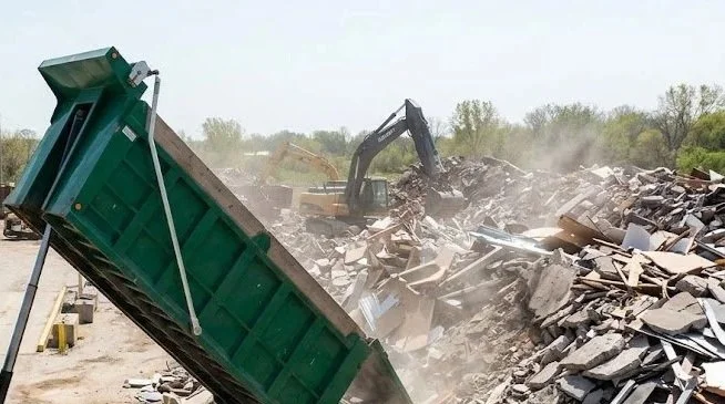 A green dumpster hauler dumping construction debris at Touby Pike Recycling.