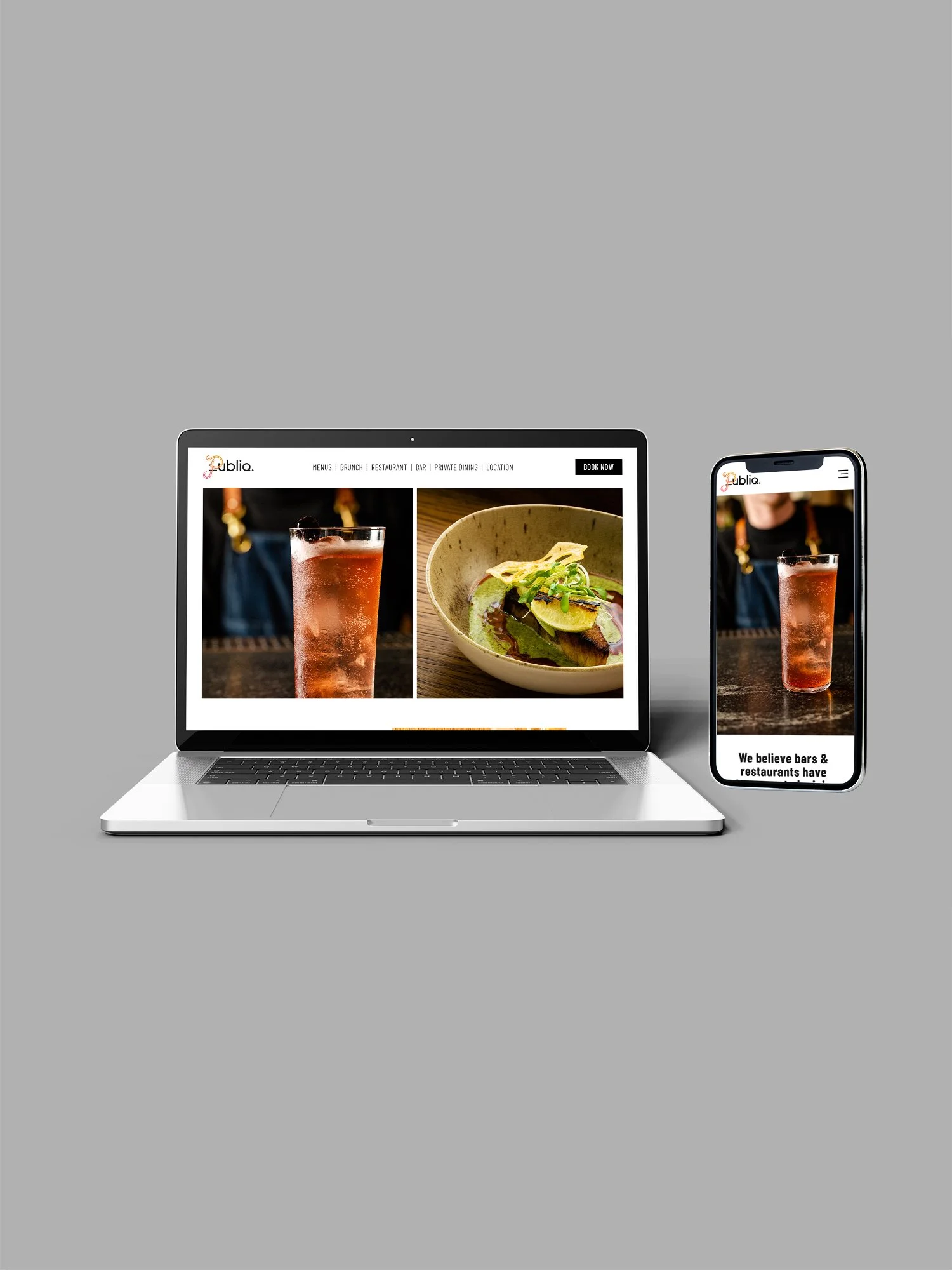 Laptop and smartphone displaying a restaurant or bar website with images of drinks and food, against a plain gray background.