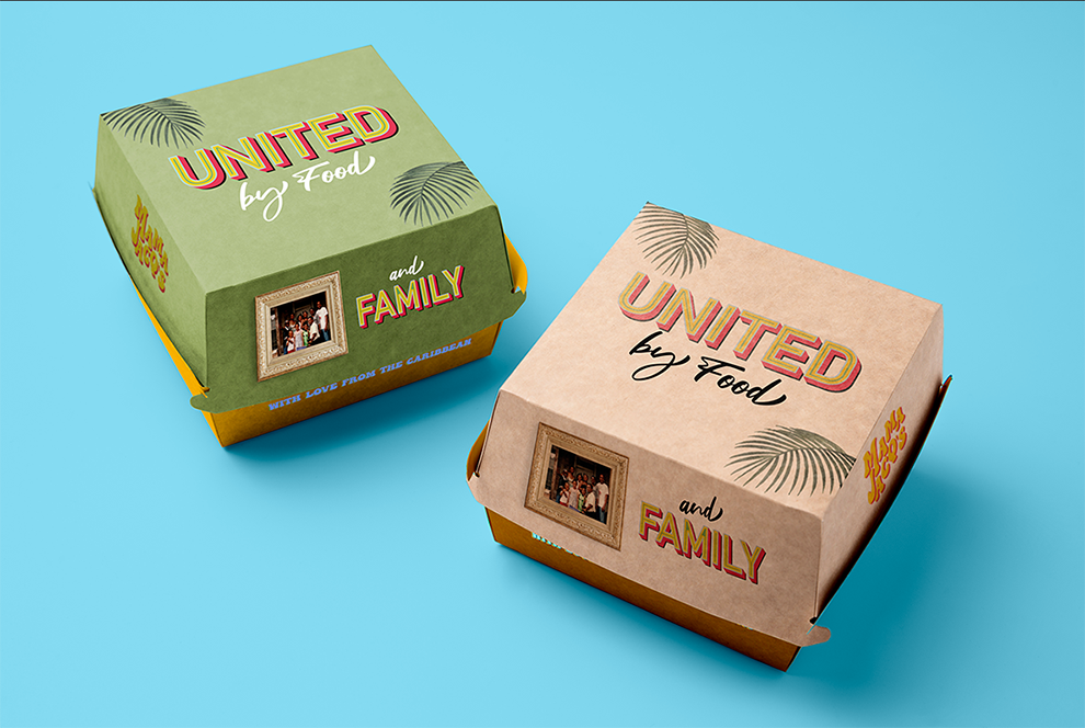 Two colorful food boxes with tropical leaf graphics and family photos, one green with yellow accents and one beige, on a blue background.