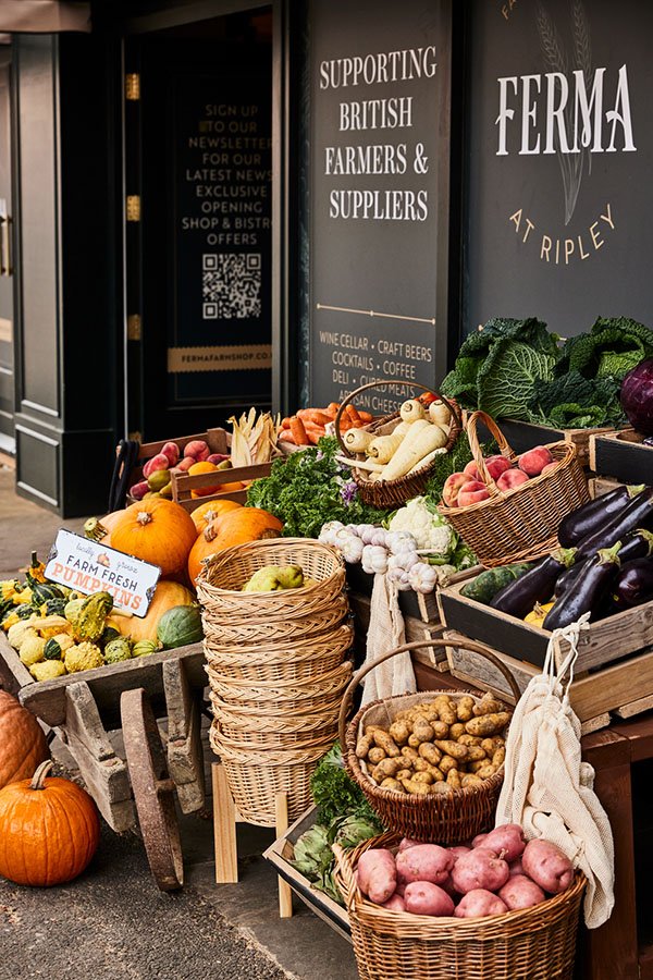Display of fresh vegetables and pumpkins outside a store with signs supporting British farmers and suppliers.