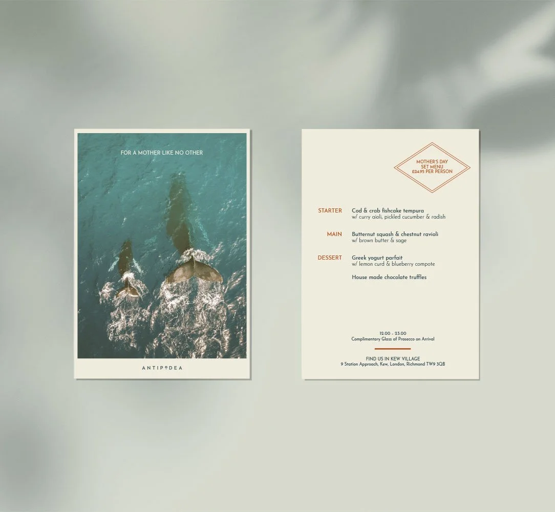 A menu for a Mother's Day set meal featuring a starter of cod and crab fishcake tempura, main of butternut squash and chestnut ravioli, and dessert of Greek yogurt parfait and homemade chocolate truffles. The menu is on a white background with orange text accents, next to a poster showing two whales swimming in the ocean.