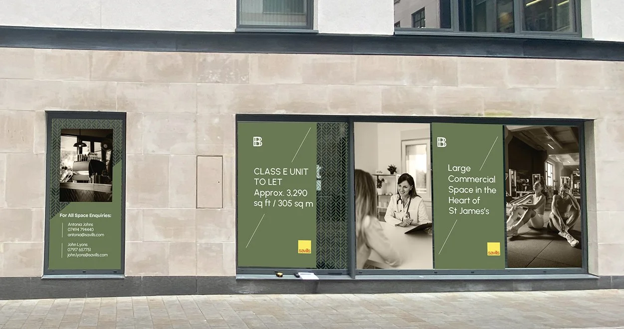 The image shows a storefront with large windows containing promotional signs. The signs advertise a commercial space for lease in St. James's, with details about the size (approximately 3,290 square feet or 305 square meters). One sign features a photo of a doctor talking to a patient, and another shows people exercising in a gym. Contact information for inquiries is listed on a smaller sign on the left side.