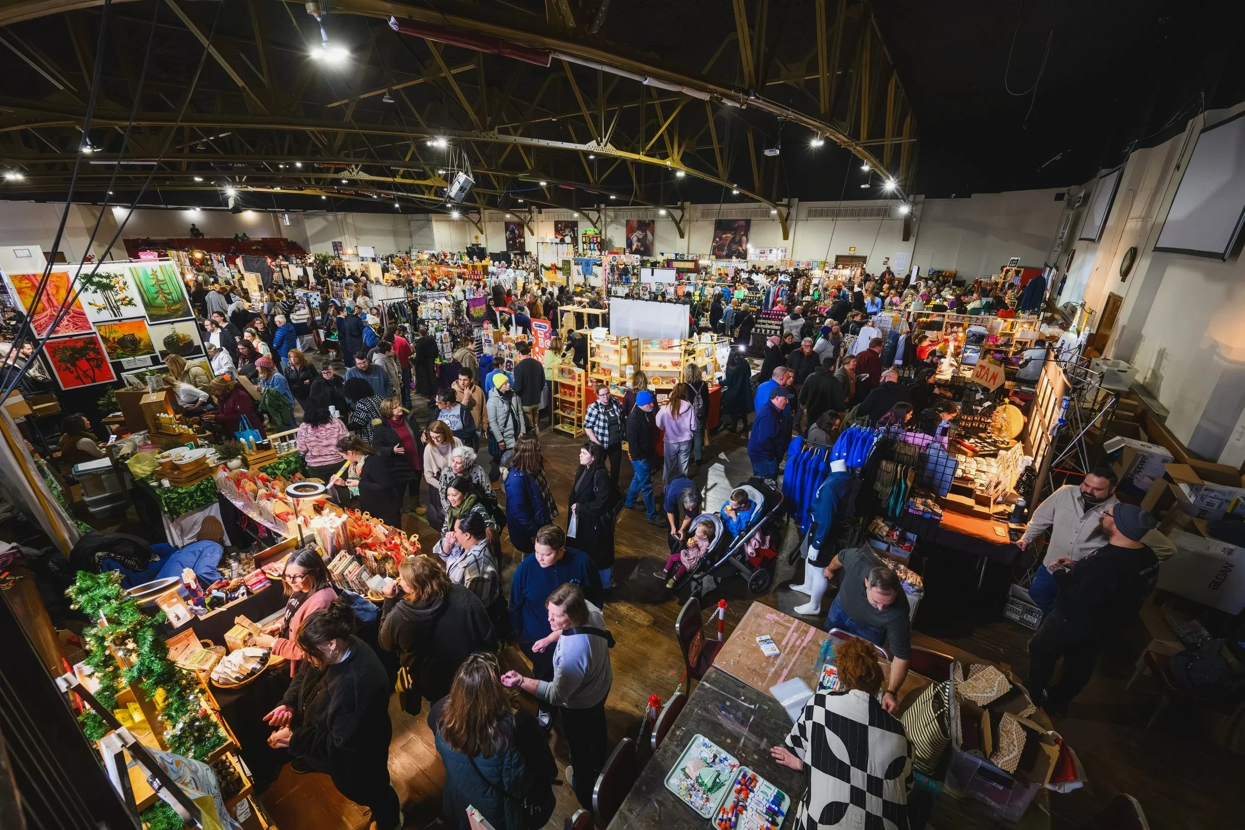 The Detroit Urban Craft Fair with numerous booths selling artwork, handmade items, and gifts with a massive crowd shopping the wares.