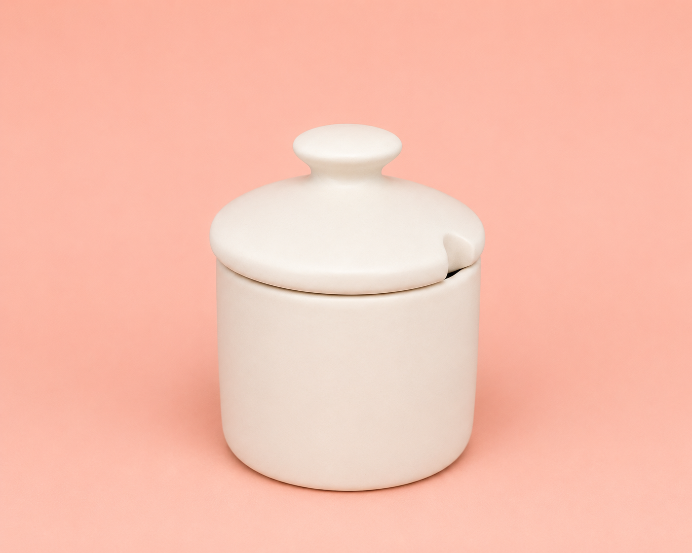Pote de cerâmica branco com tampa, sobre fundo rosa