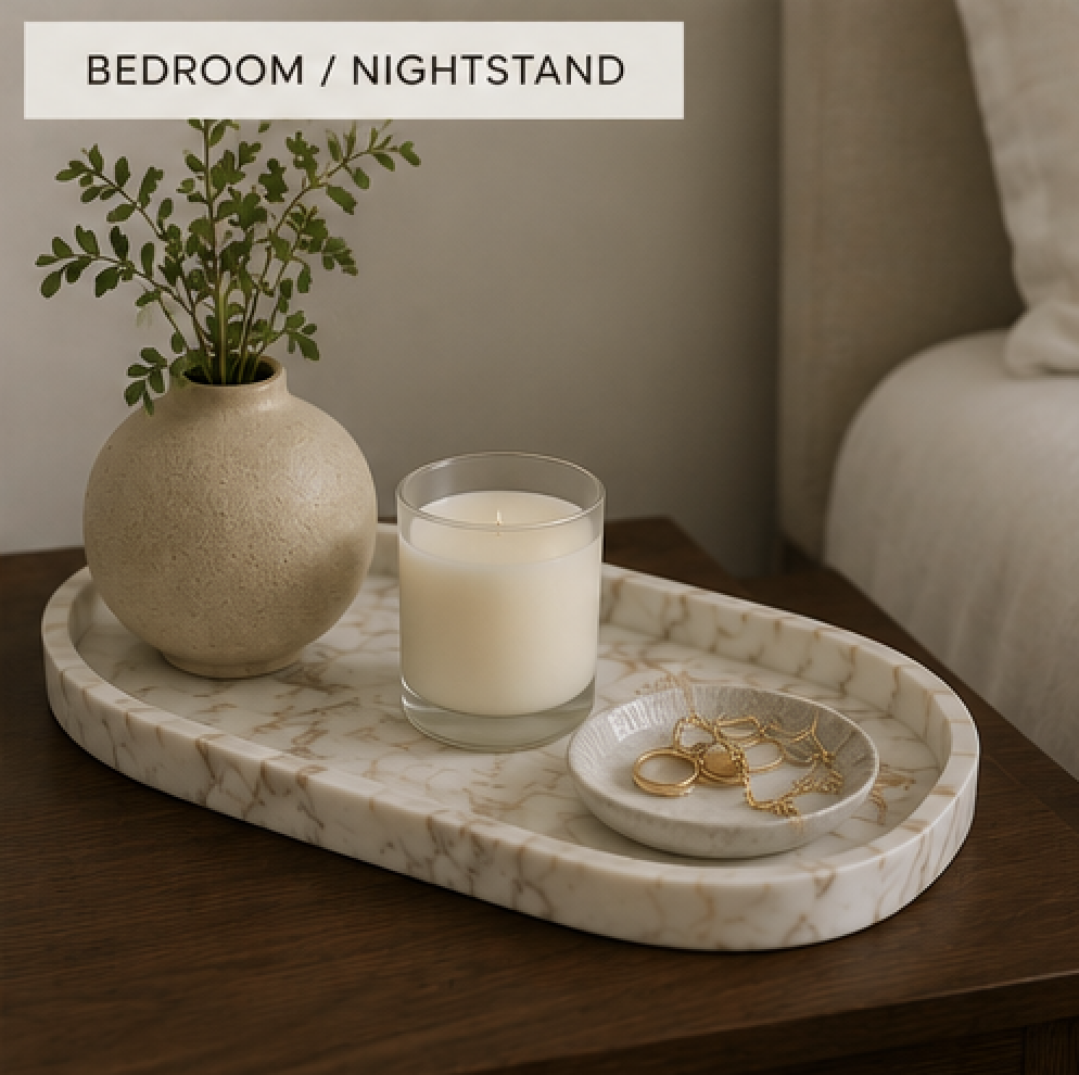 Marble tray on a bedroom nightstand holding jewelry, a candle, hand cream, and a ceramic vase to create a calm bedside arrangement.