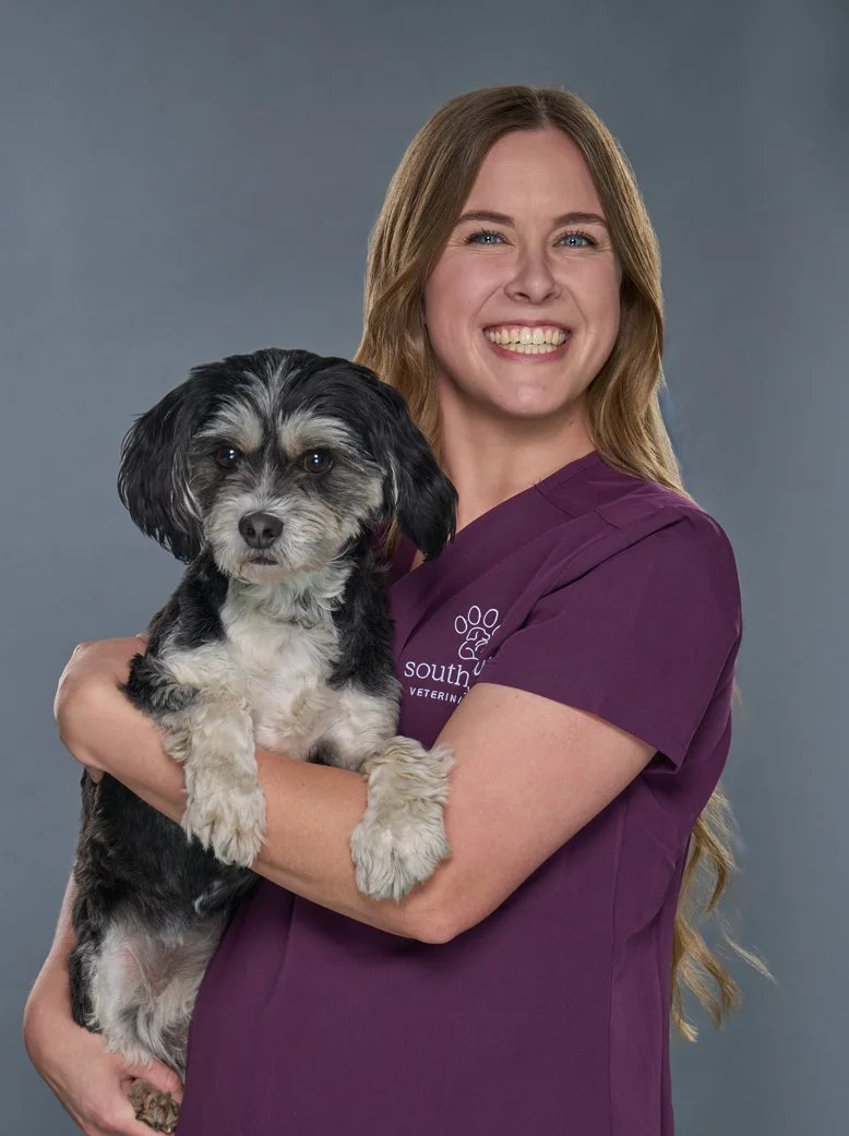Jesse headshot, woman with long hair and in purple scrubs and holding her dog