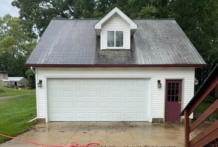 Asphalt shingle garage roof after initial soft wash treatment with remaining organic growth