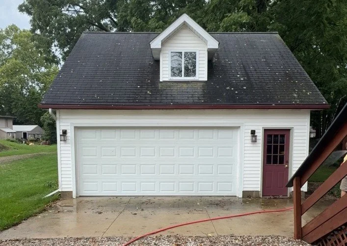 Asphalt shingle garage roof with visible organic growth before soft wash treatment