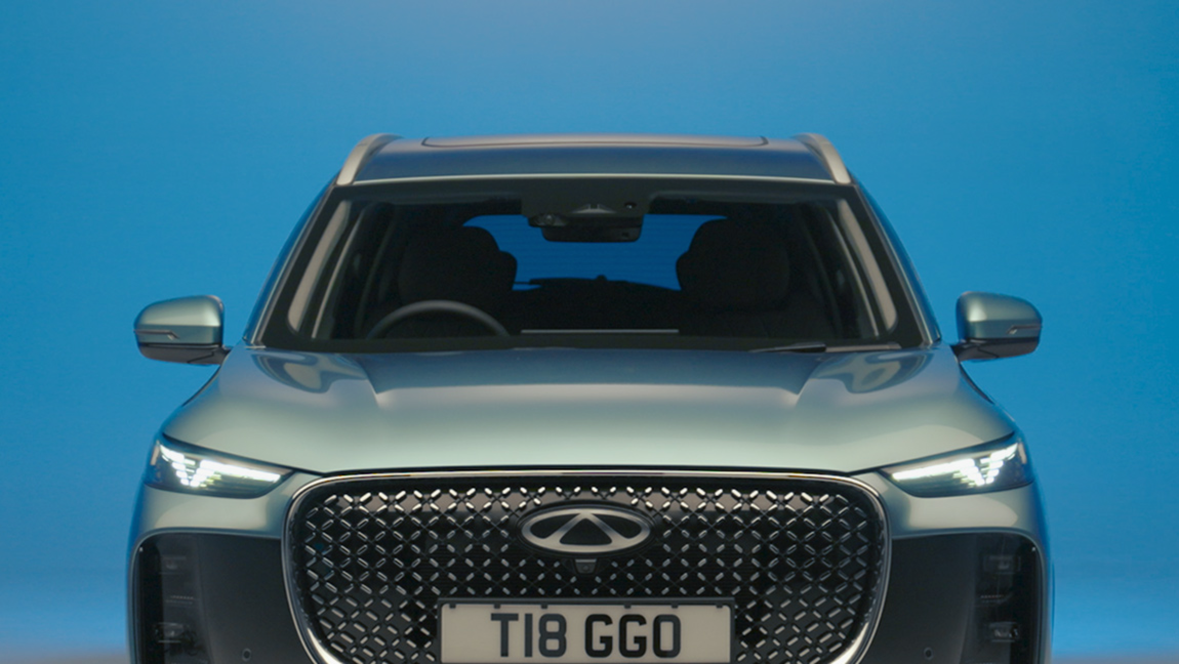 Front view of a modern compact SUV with a prominent grille and LED headlights, set against a blue background.