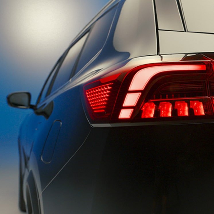 Close-up of the rear of a black modern SUV with illuminated red tail lights.