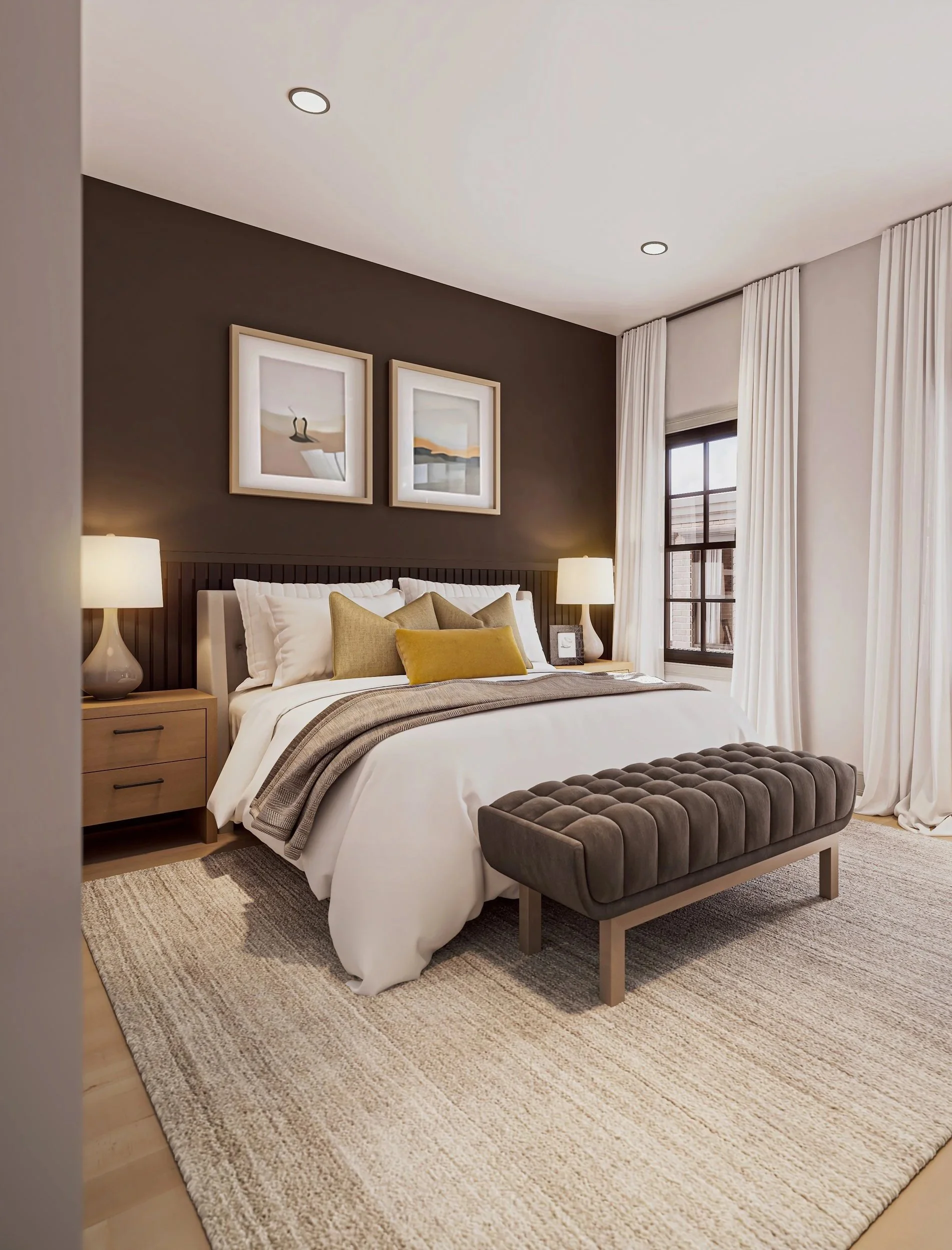 A cozy bedroom with a large bed, beige and white bedding, and a yellow accent pillow. Two bedside tables with white lamps flank the bed. Two framed artworks hang on a dark accent wall above the headboard. A gray tufted bench sits at the foot of the bed. Light-colored curtains frame a window, letting in natural light. A patterned area rug covers the wooden floor.