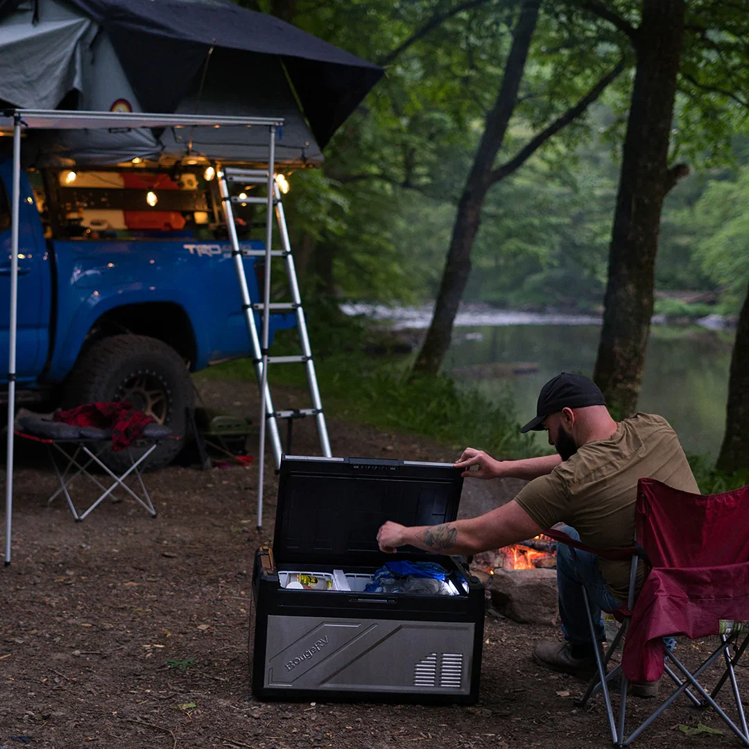 BougeRV Rocky fridge at a forest campsite beside a rooftop tent vehicle