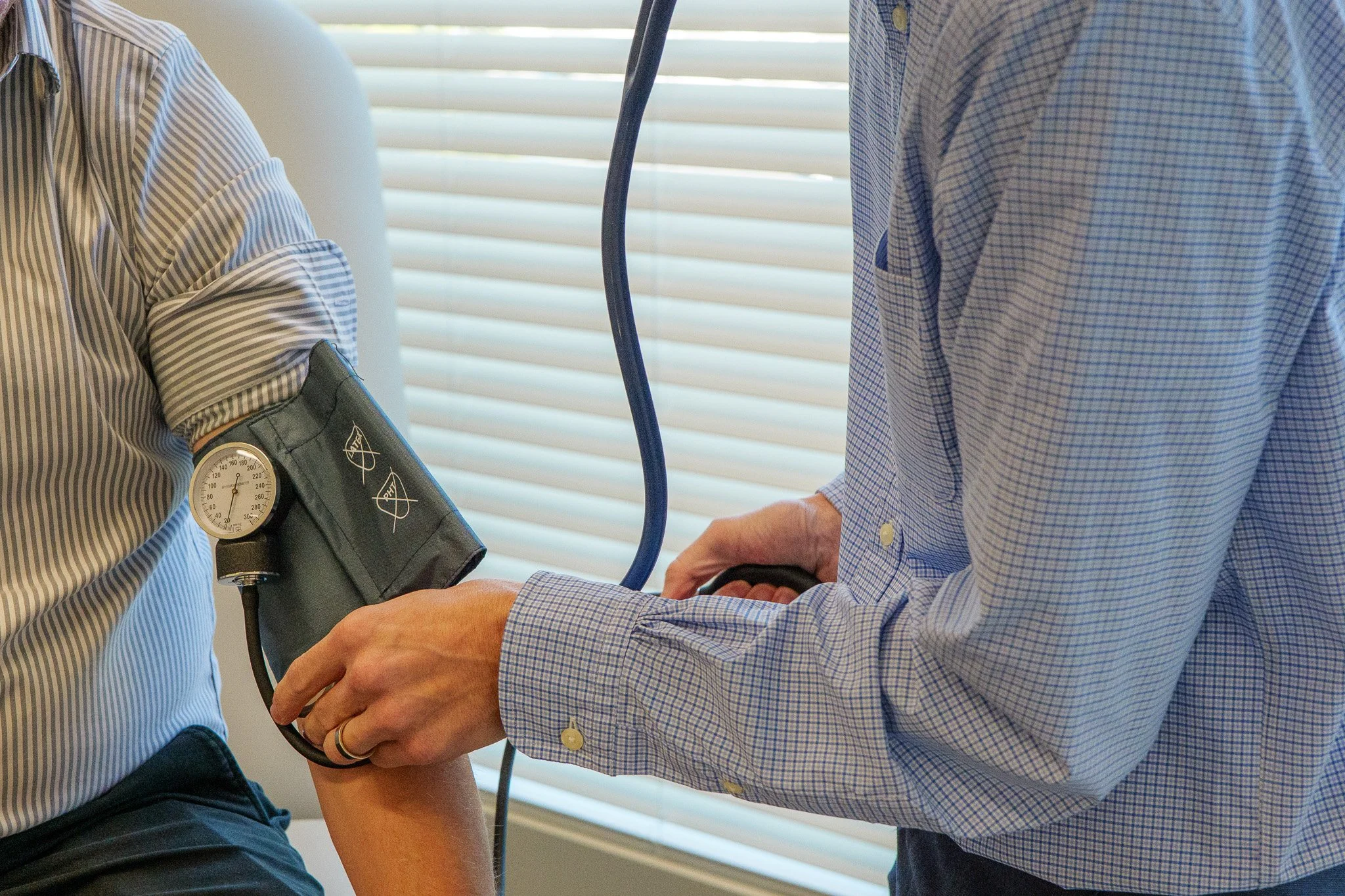 Medical professional measuring a patient's blood pressure with a manual cuff and gauge