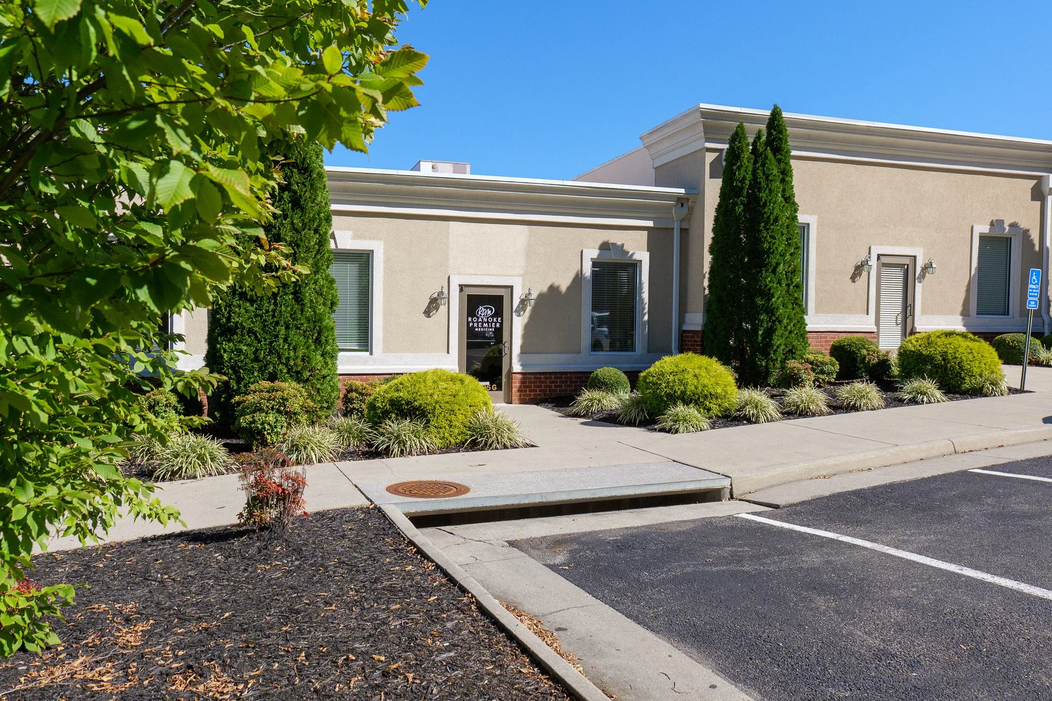 Exterior of Roanoke Premier Medicine medical office building with landscaped shrubs, sidewalk, and accessible parking.