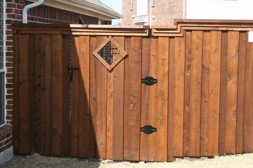 Wooden fence with a small diamond-shaped window and a black fish-shaped decoration.