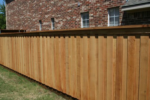New wooden privacy fence beside a brick building
