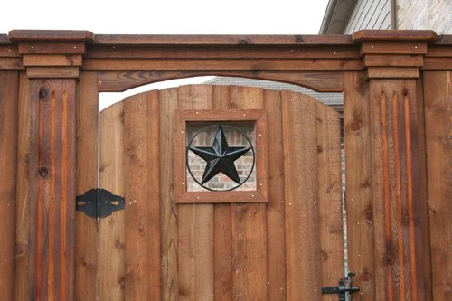 A wooden gate with a star-shaped decoration in a small window at the top center, framed by wooden posts.