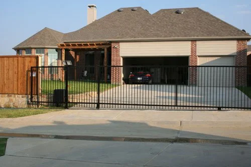 Front view of a house with a fenced yard, garage, and a car parked inside the garage.