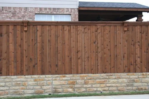 Wooden privacy fence with a brick house in the background.